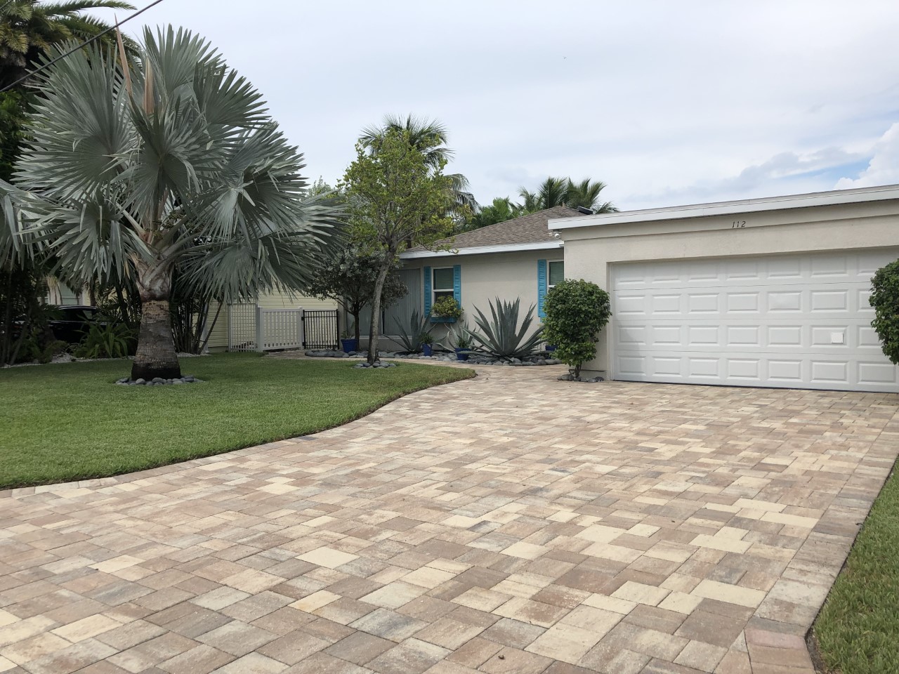 Suburban house with paver driveway and palms