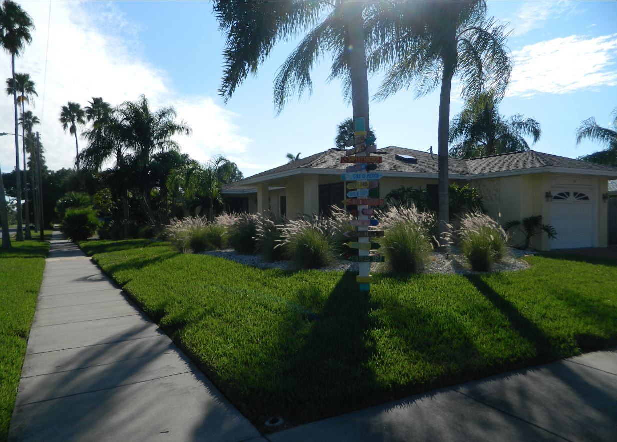 Suburban house with palm trees, sidewalk, lawn