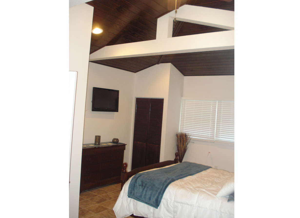 Bedroom with vaulted dark wood ceiling