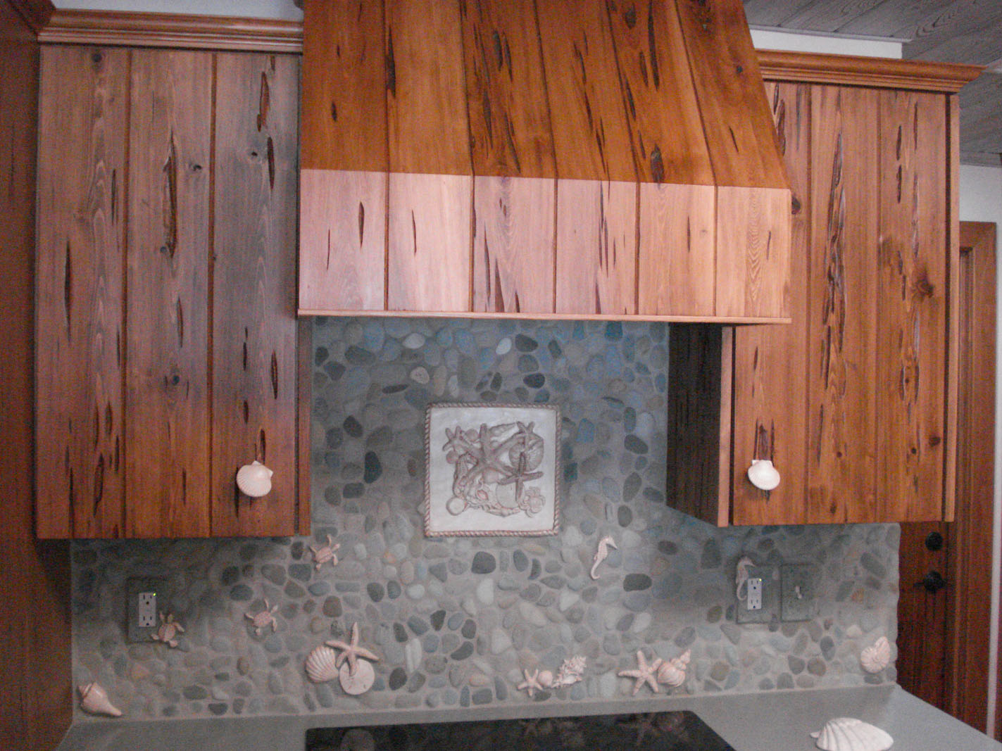 Wood cabinets with pebble and seashell backsplash