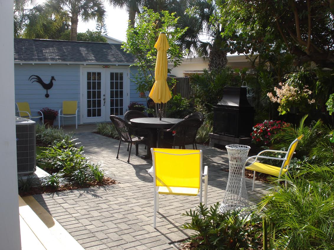 Sunny backyard patio with yellow chairs and umbrella