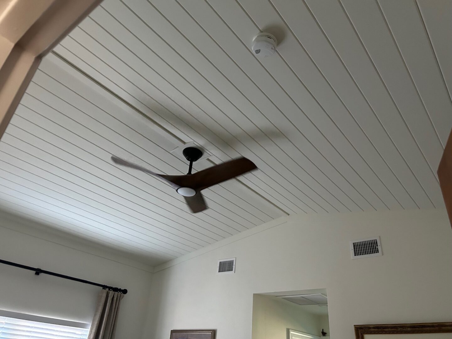 Three-blade ceiling fan on white paneled ceiling